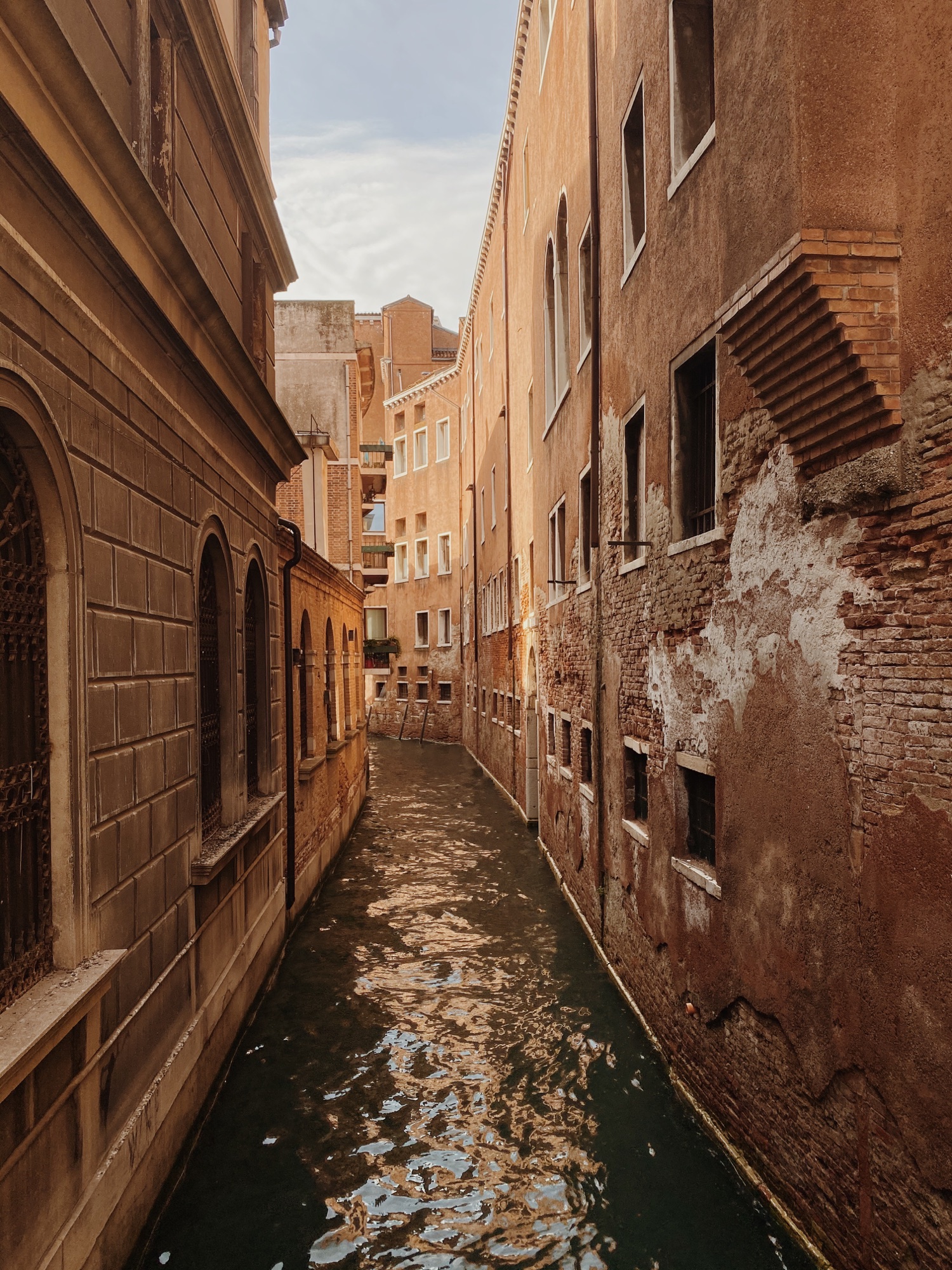 A narrow canal between warm brick buildings in Venice