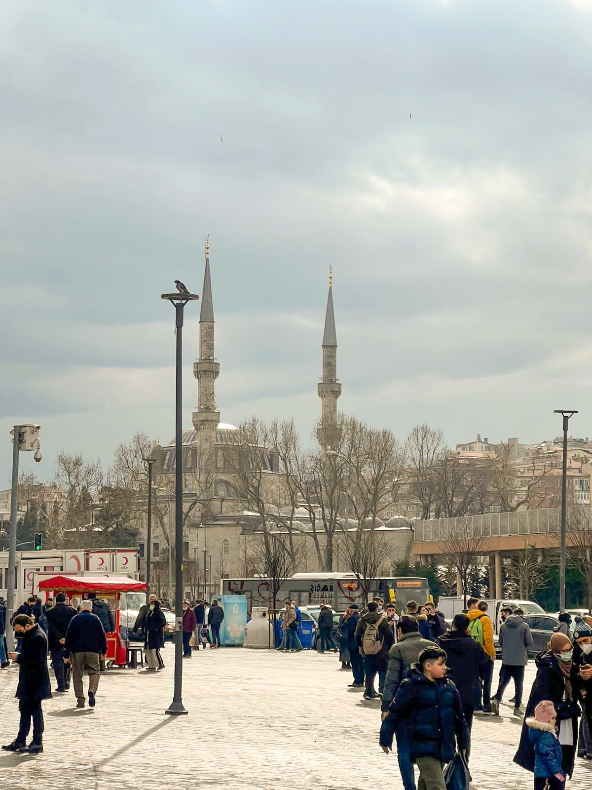 Crowded city square with a mosque beyond